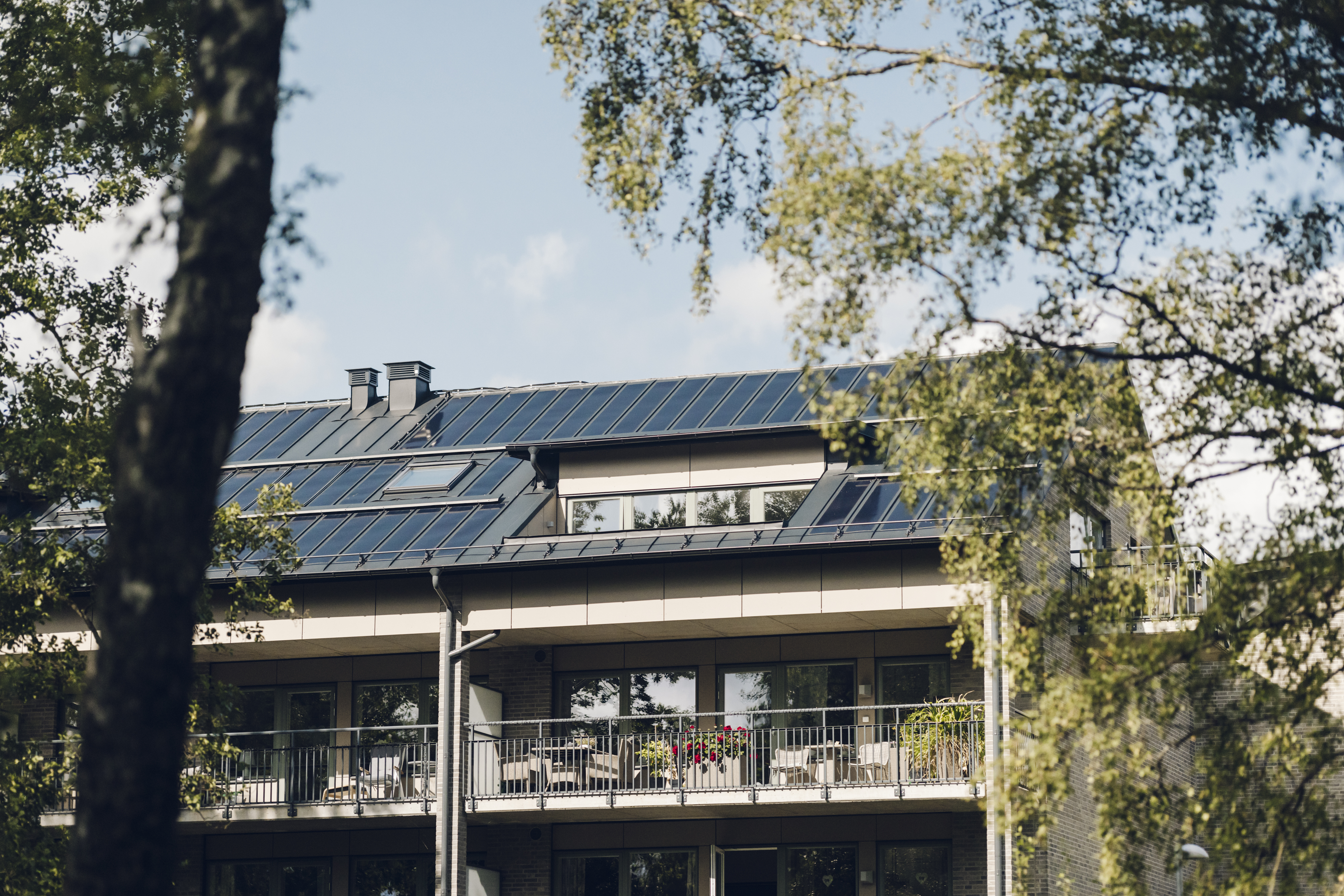 Svart tak med solceller på höghus i beige tegel